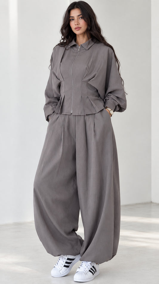 Model wearing grey zip-front top and balloon pants matching two-piece set front view
